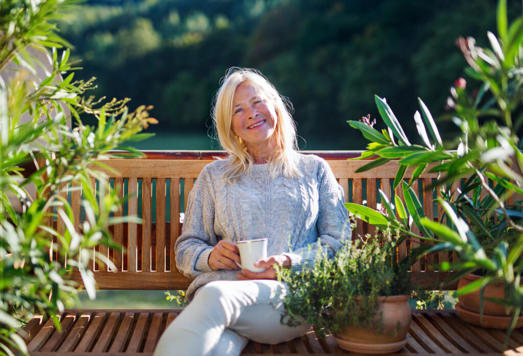 אישה מבוגרת עם כוס תה על ספסל