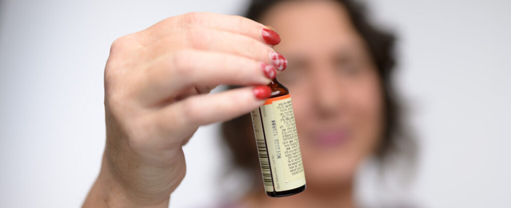 טיפול טבעי בדלקות אזניים - רביד מחזיקה בקבוקון תמצית פרחי באך