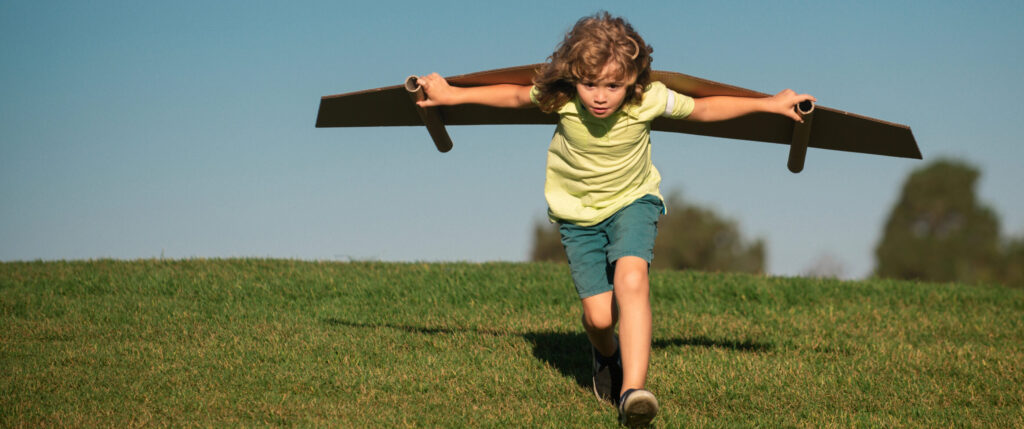 ילד משחק עם כנפי עץ שבנה כמו אווירון - תמצית קלמטיס לילד עפיפון